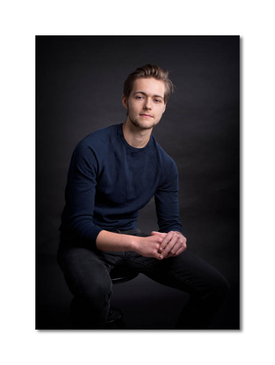 actor , headshot, sitting on a stool