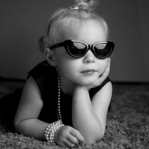 young girl with pearls and sunglasses audrey hepburn style